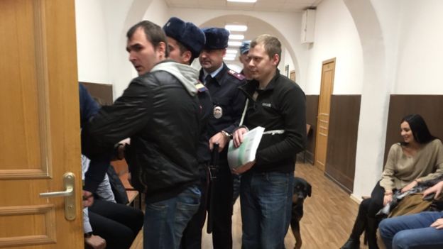 Конвой заводит двоих мужчин в судебный зал