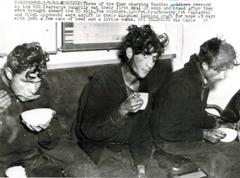 Фото из американского архива: голодные советские моряки (подписано голубым над зачеркнутым «солдаты») едят первый раз после спасения. Интересно, что в американскому описании упоминается, что у экипажа во время 49-дневного дрейфа была водка